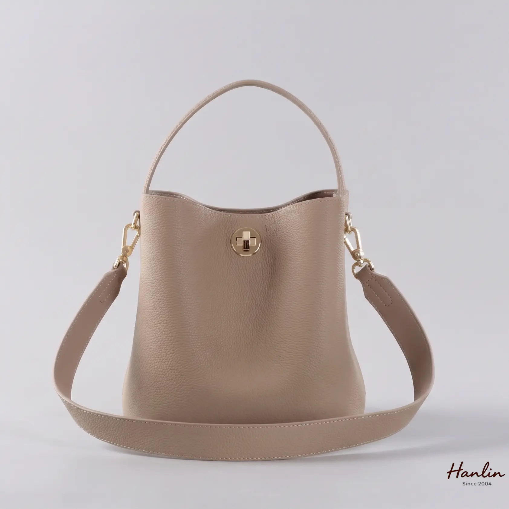 حقيبة دلو بيج اللون مزودة بحزام للكتف.