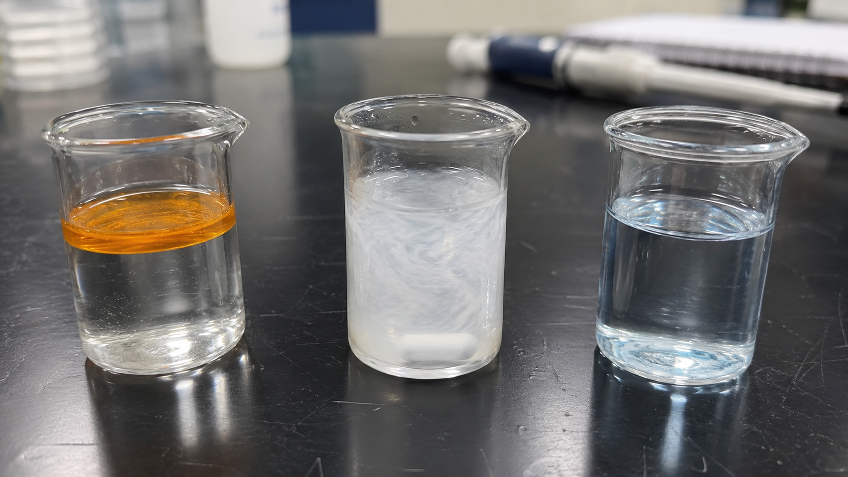 界面活性剤の混合および油の乳化のさまざまな段階を示す実験室用ベンチマークビーカー